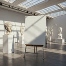 Empty easel in bright modern art gallery with sculptures