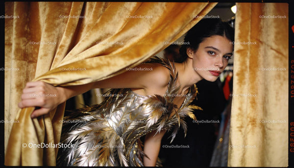 Model peeking through golden curtains in metallic dress