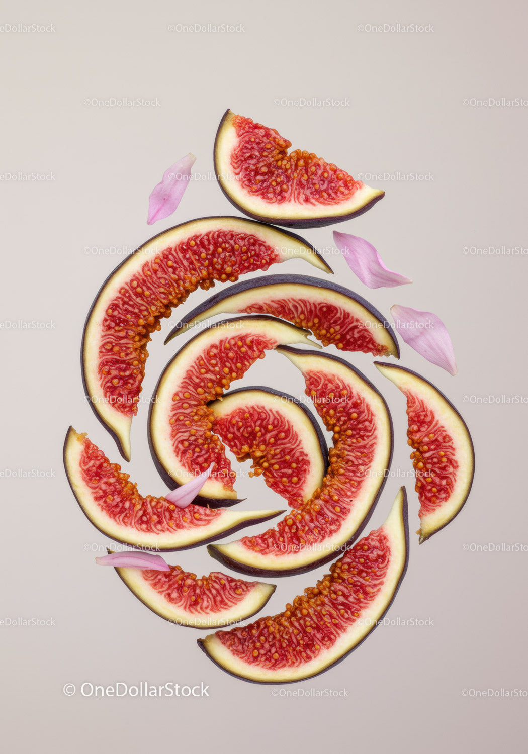 Sliced fresh figs with pink flower petals on beige