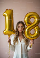 Young woman celebrating 18th birthday with gold balloons