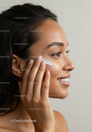 Portrait of a woman applying facial moisturizer demonstrating skincare routine