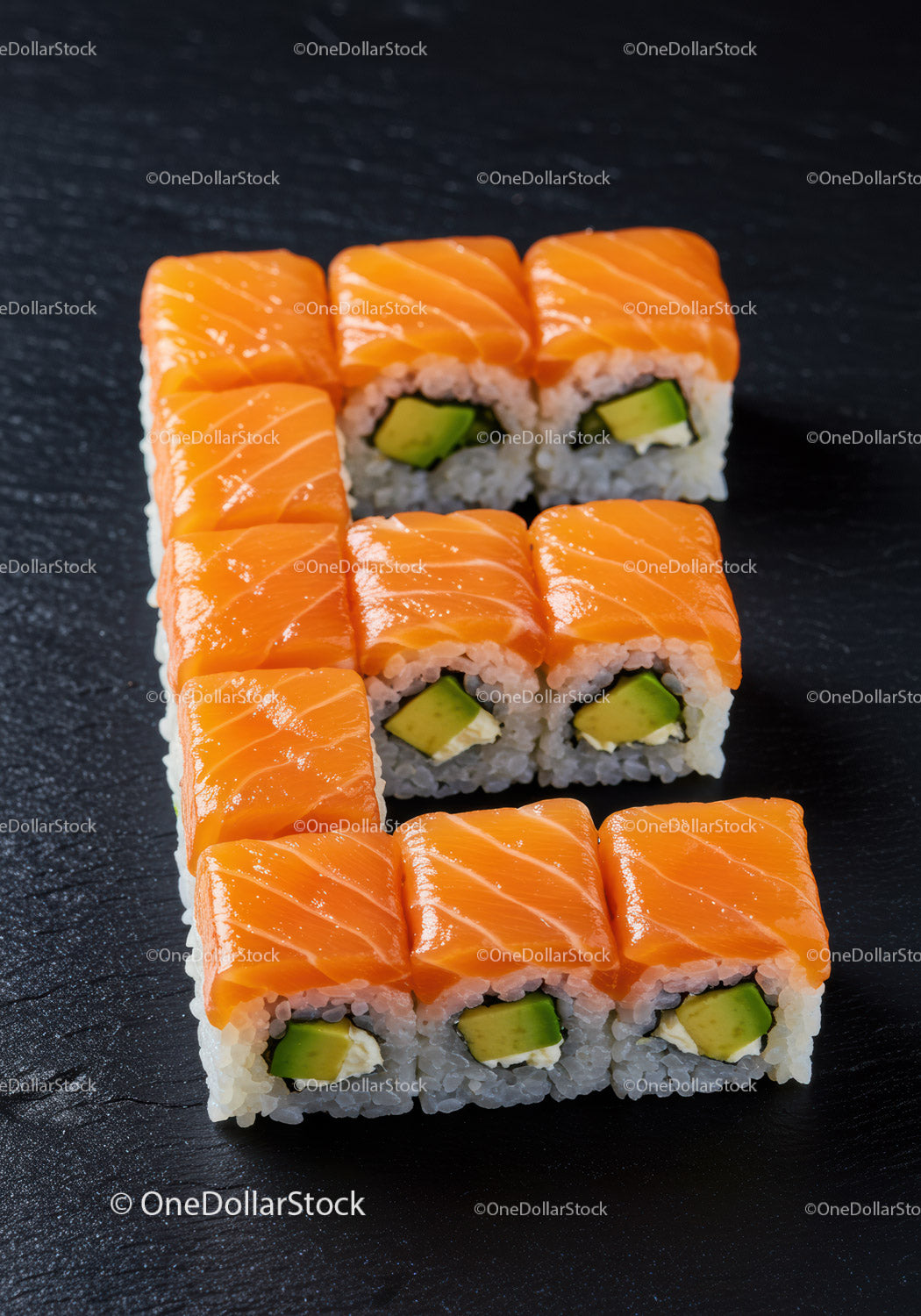 Rolki sushi z łososiem i awokado ułożone na czarnym łupku