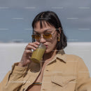 Stylish Woman Sipping Green Smoothie on Sunny Beach