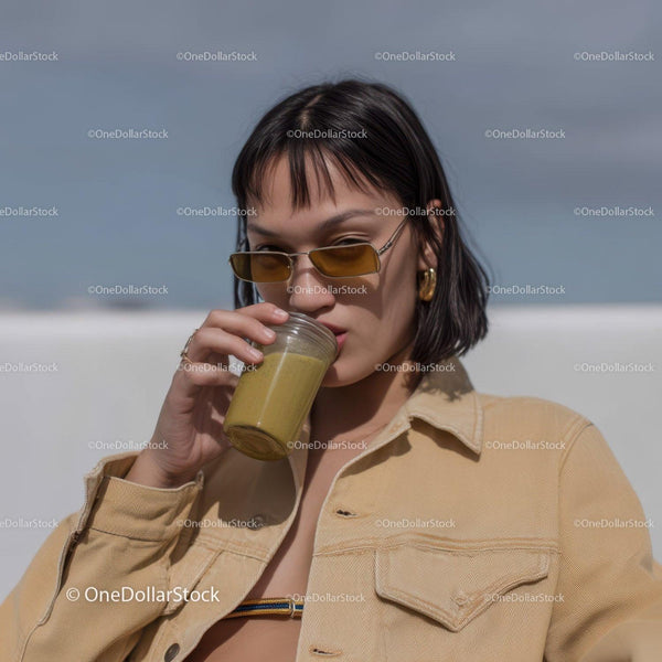 Stylish Woman Sipping Green Smoothie on Sunny Beach