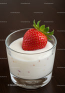 Fresh strawberry resting on creamy yogurt in glass