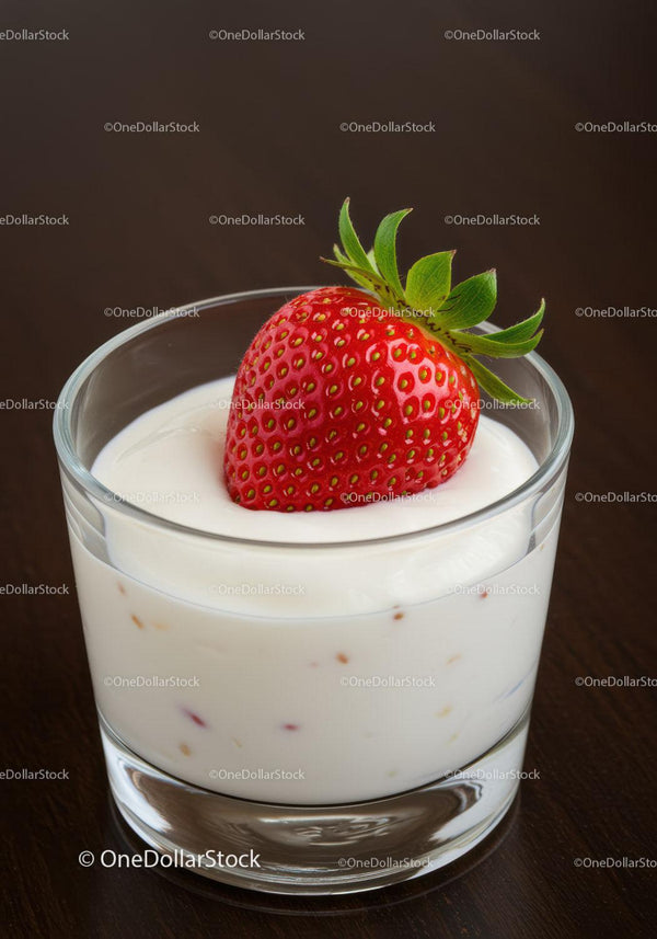 Fresh strawberry resting on creamy yogurt in glass