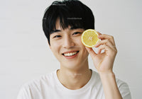 Young Man Smiling with Lemon Slice in Hand Bright Natural Portrait
