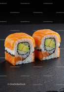 Fresh salmon and avocado sushi rolls on black slate