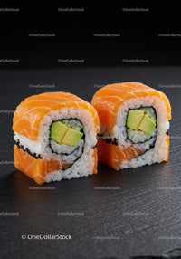 Fresh salmon and avocado sushi rolls on black slate