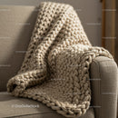 Cozy beige chunky knit blanket on textured armchair