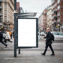 Man walking past blank advertising board in city street