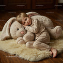Young boy resting with giant plush bunny indoors