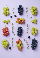 Variety of fresh grapes and thyme sprigs on pastel surface