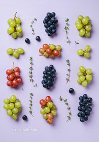 Variety of fresh grapes and thyme sprigs on pastel surface