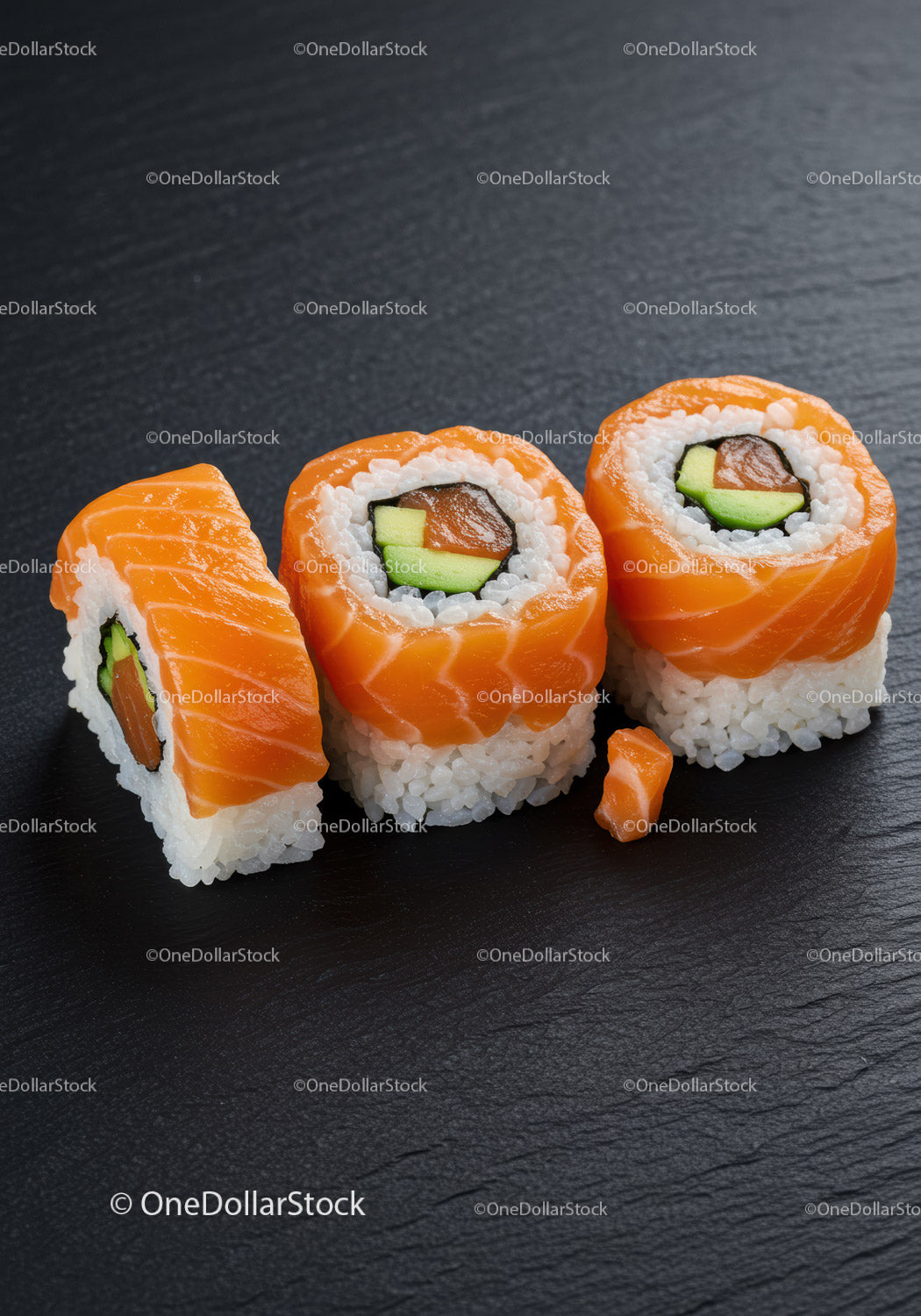 Fresh salmon sushi rolls with avocado on black slate