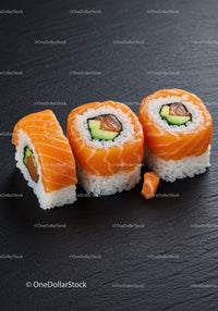 Fresh salmon sushi rolls with avocado on black slate