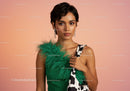 Elegant Woman in Green Dress with Feather Details on Soft Pink Background