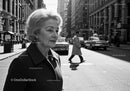 Elderly Woman in Busy City Street Surrounded by Vintage Cars