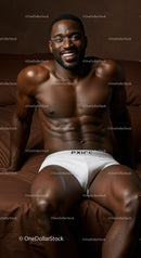 Smiling muscular man relaxing on brown bed in white briefs