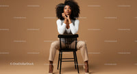 Elegant Woman in Beige Pants and White Top Sitting on Black Chair