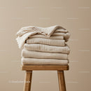 Stack of neutral toned cozy folded blankets on stool