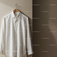 White button-up shirt hanging on wooden hanger