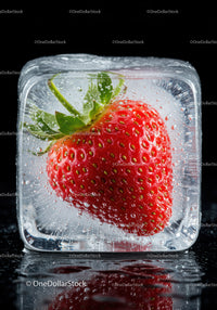 Fresh strawberry frozen inside a clear ice cube