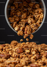 Crunchy granola clusters pouring from metal container