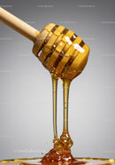 Golden honey dripping slowly from wooden dipper