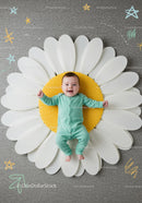 Happy baby lying on large decorative daisy flower mat