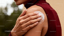 Woman Applying Moisturizing Cream to Shoulder Outdoors