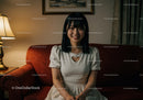 Portrait of a Happy Young Woman Sitting on a Couch in a Cozy Living Room
