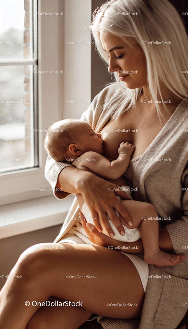 Mama karmiąca piersią swoje dziecko przy nasłonecznionym oknie
