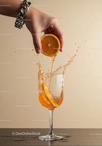 Hand Squeezing Fresh Orange into Glass with Splash