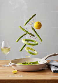 Fresh asparagus and lemon slices cooking in pan