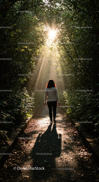 Woman walking under sunlit forest canopy path