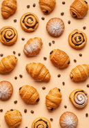 Assorted fresh pastries with coffee beans on beige surface