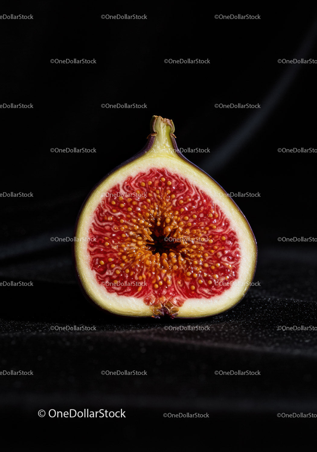 Close-up of ripe fig cut in half on black background