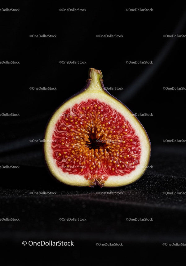 Close-up of ripe fig cut in half on black background
