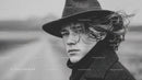 Black and White Portrait of a Young Man with Curly Hair Wearing Fedora