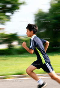 Young boy running swiftly through park pathway