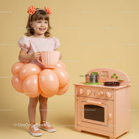 Smiling little girl in balloon skirt holding giant cup