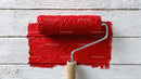 Red Paint and Painting Roller On White Wooden Surface