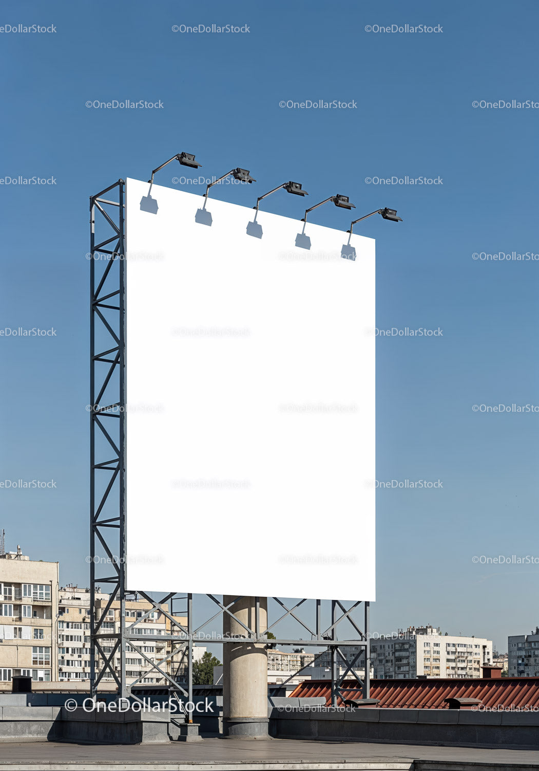 Large blank billboard on urban rooftop against clear sky