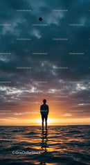 Silhouette of man standing in water at sunset