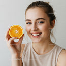 Bright Smiling Woman Holding Fresh Orange Slice for Wellness and Summer Vibes