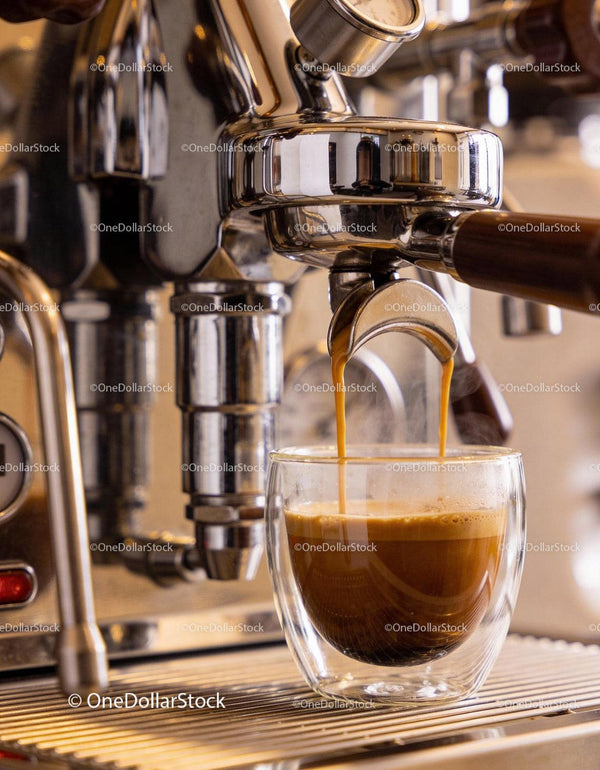 Fresh espresso pouring into double-walled glass cup