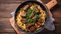 Beef Stroganoff with Pasta Garnished with Fresh Herbs on Rustic Table