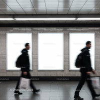 Blurred commuters walking past blank urban billboards
