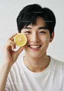Young Man with Lemon Slice Smiling Brightly in a Minimalist Studio